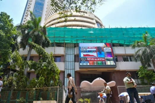 Mumbai: People walk past a screen showing stock market goes down outside BSE building at Dalal Street after the counting of votes for Lok Sabha polls