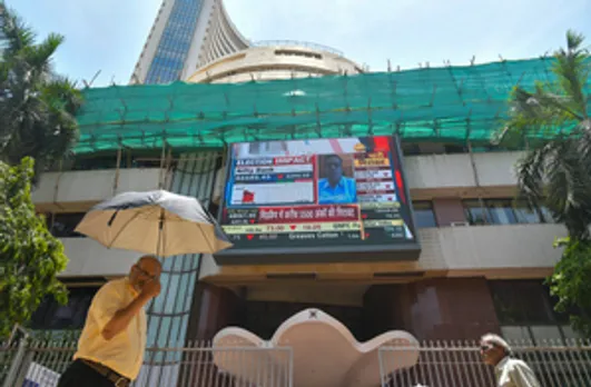 Mumbai: People walk past a screen showing stock market goes down outside BSE building at Dalal Street after the counting of votes for Lok Sabha polls