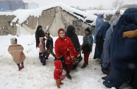Afghan refugees wait to receive winter relief supplies in Kabul