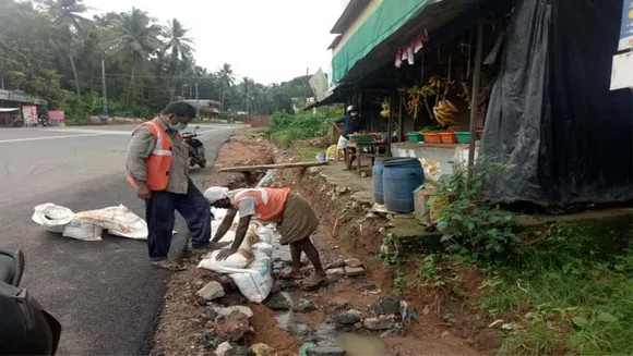 അശാസ്ത്രീയമായി നിർമിച്ചിട്ടുള്ള റോഡ് കുത്തിയൊലിച്ചു പോകാതിരിക്കാൻ മണൽ ചാക്ക് തടയണ; കരാർ കമ്പനിയുടെ നടപടി ജനത്തിന്റെ കണ്ണിൽ പൊടിയിടാൻ