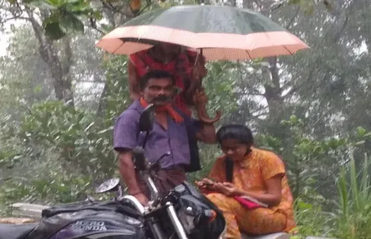 മഴയില്‍ റോഡരികില്‍ ഓണ്‍ലൈന്‍ ക്ലാസില്‍ പങ്കെടുത്ത് മകള്‍ ; കുടപിടിച്ച് അച്ഛനും ; ചിത്രം വൈറലായി
