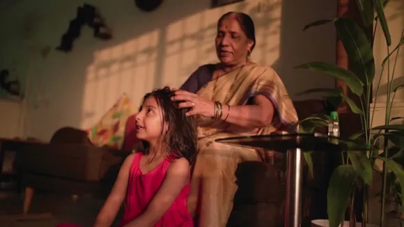 Grandmother putting hair oil in her grand daughters hair