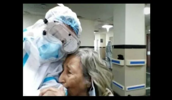 elderly woman hugging PPE-clad doctor