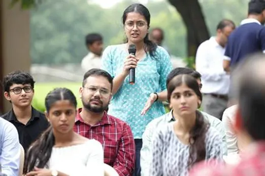 A person holding a microphone in front of a group of peopleAI-generated content may be incorrect.