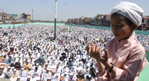 खुले आसमान और खिली तेज धूप में ईद के मौके पर नमाज अदा करता नन्हा नमाजी।