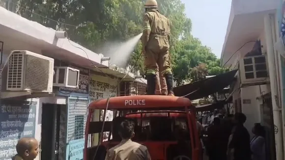 वकील के बस्ते के ऊपरी हिस्से में लगी आग बुझाता फायरकर्मी। 