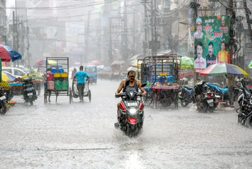 Commuters wade through heavy rainfall in Patna on Friday