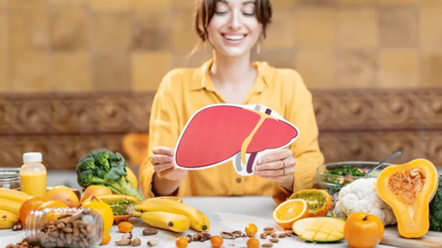 Woman holding a liver illustration surronded by healthy foods