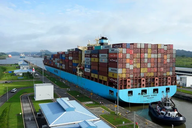 A cargo ship and tugboat move through the Panama Canal 