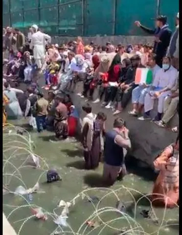 কাবুল বিমানবন্দরে প্রবেশের জন্যে নর্দমায় দাঁড়িয়ে ভিক্ষা আফগানবাসীর