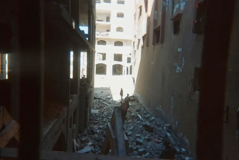 This photo provided by Breaking the Silence, a whistleblower group of former Israeli soldiers, shows two soldiers behind Palestinian detainees being sent into a Gaza City-area house to clear it