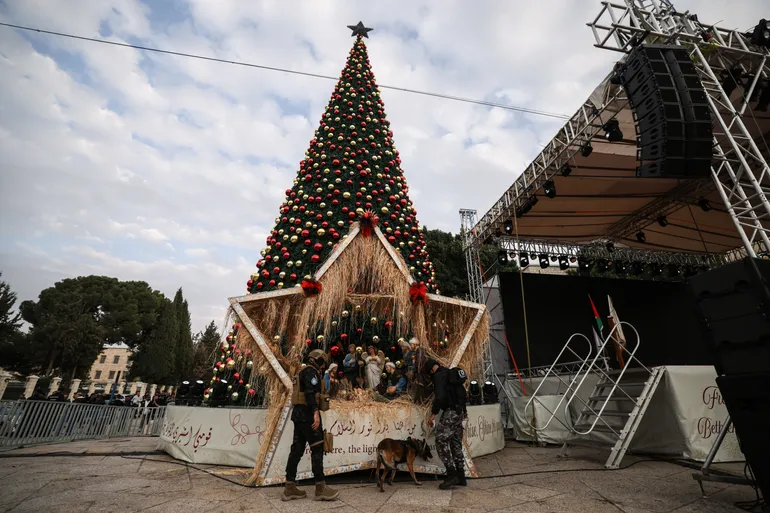 A Palestinian police officer from the K9 unit checks Christmas decorations before a Christmas tree lighting ceremony in Bethlehem, in the Israeli-occupied West Bank, on December 6, 2025. (Photo by HAZEM BADER / AFP)