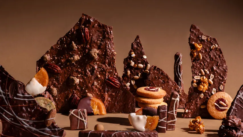 A zoomed in shot of a range of chocolate thins and chocolates with bits of orange and walnut strewn around to show how Indian chocolatiers are using Indian cacao to make artisanal chocolate in India, and changing chocolate gifting in India