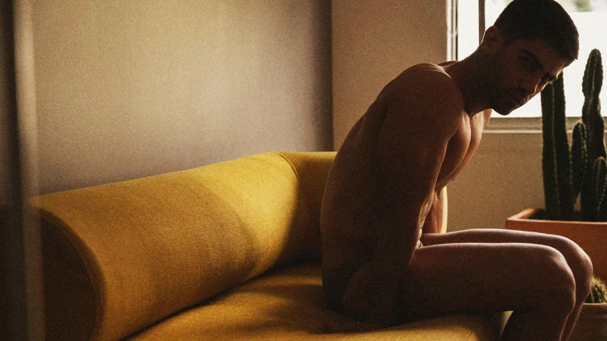 A picture of a man sitting in silence on a mustard couch