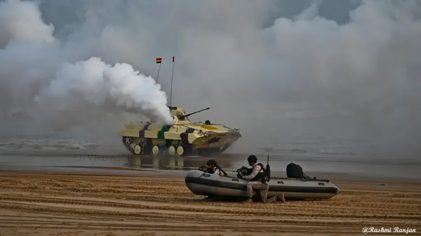 A Navy tank charges through the rugged terrain, surrounded by smoke and water splashes, displaying.