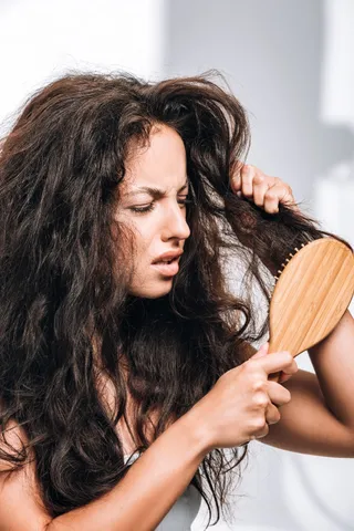 confused-brunette-woman-styling-unruly-curly-hair-2023-11-27-05-18-35-utc (1)