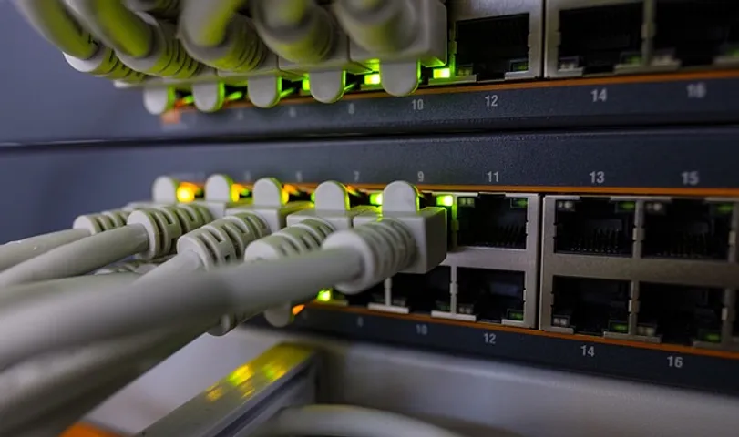 A close-up photo of a black rectangular electronic device with a variety of ports and flashing lights on the front panel.