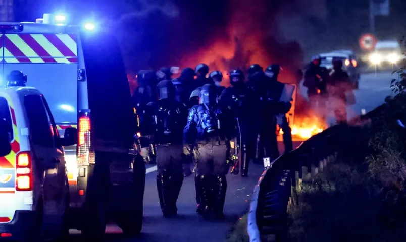 Police walk near tires burning at a blockade in Nantes France REUTERS