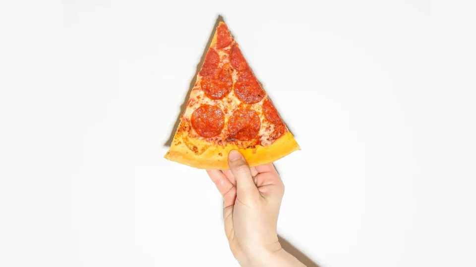 A slide of pizza in India in man's hand