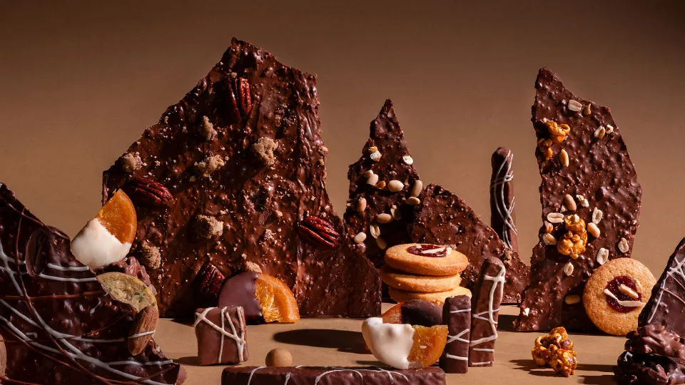 A zoomed in shot of a range of chocolate thins and chocolates with bits of orange and walnut strewn around to show how Indian chocolatiers are using Indian cacao to make artisanal chocolate in India, and changing chocolate gifting in India