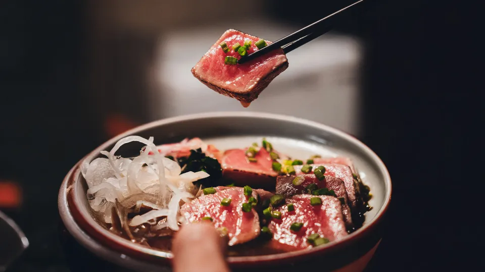 Close-up of tuna sashimi served in an izakaya-style dish with onions and scallions in India