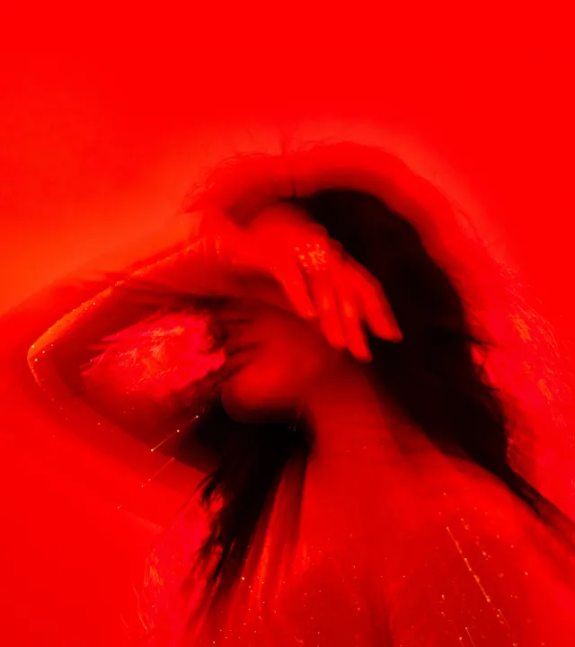 A picture of a woman against a red backdrop struggling with stress and periods