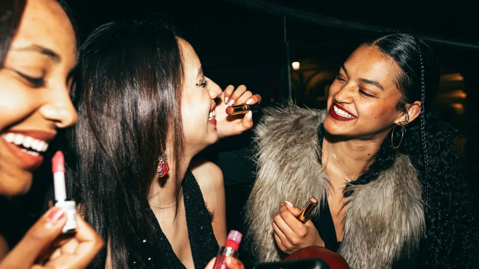 Three Gen Z girls applying make-up