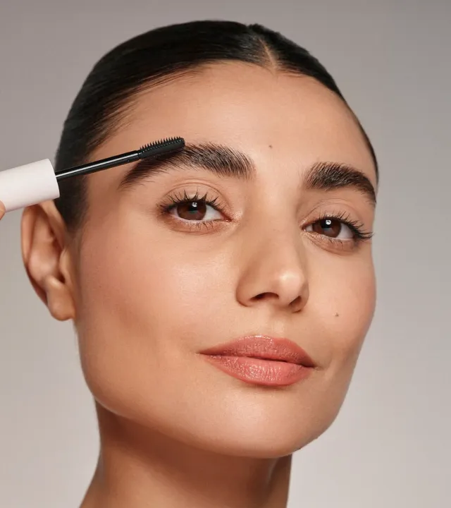 A picture of a woman applying a brow gel from her eyebrow grooming kit