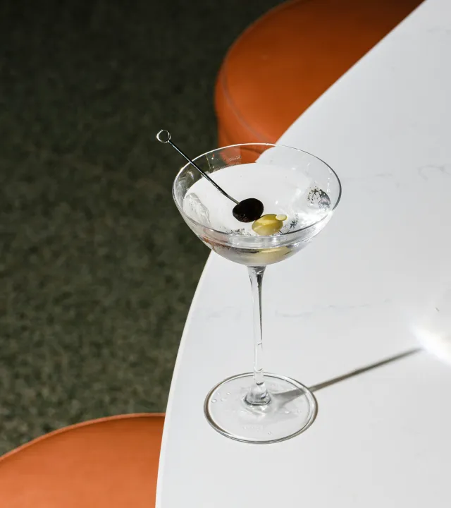A glass of gin with one black and one green olive dipped into it to represent the rise of Indian craft gins, which acing the Indian botanical gins game.