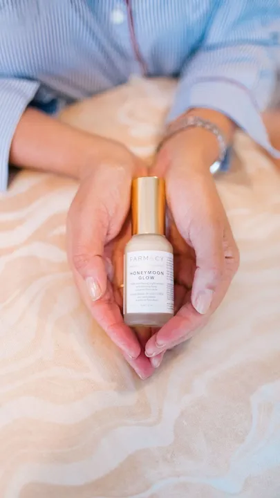 A lactic acid serum in a woman's palms against a flesh-toned backdrop