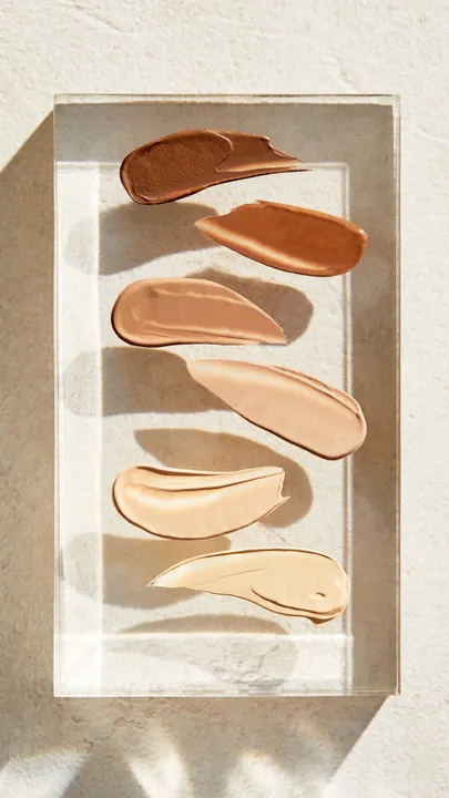 Swatches of the best skin tints in India on a glass piece placed on a marble table