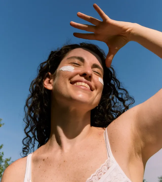 A woman with sunscreen on her cheeks with curly hair out in the sun