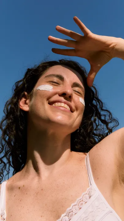 A woman's face with swipes of sunscreen on the cheeks