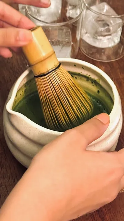 A woman whisking up matcha in a bowl