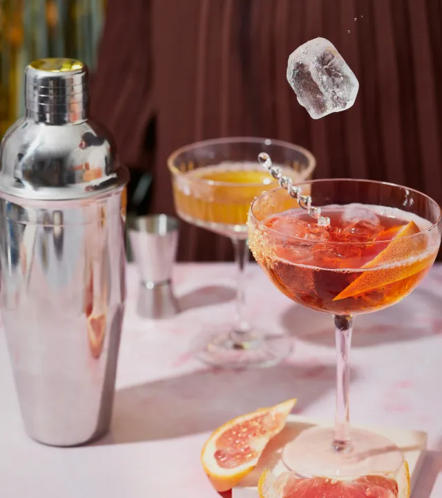 A picture with two cocktails, a shaker and ice to show the home bar essentials needed for a home bar setup including essential liquors for home bar, essential glasses for home bar and cocktail equipment at home, including premium barware India getting popular