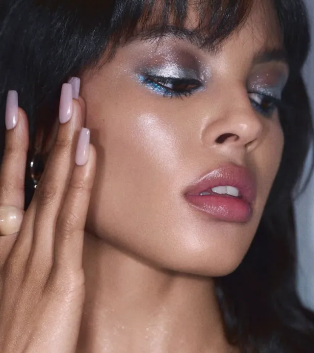 A picture of a model with frosted blue eyeshadow on her eyes with nude sheeny lips