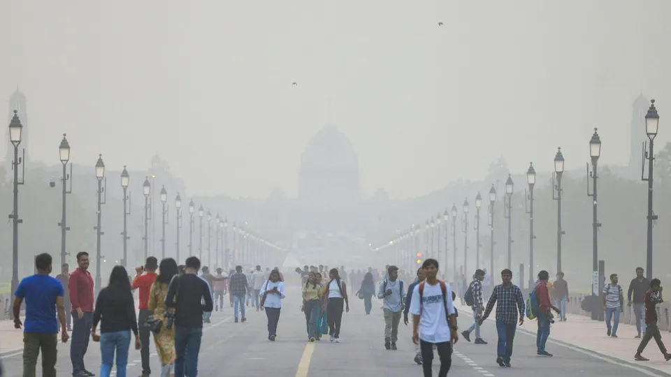 People walk on the Kartavya Path as smog shrouds Raisina hill, in New Delhi