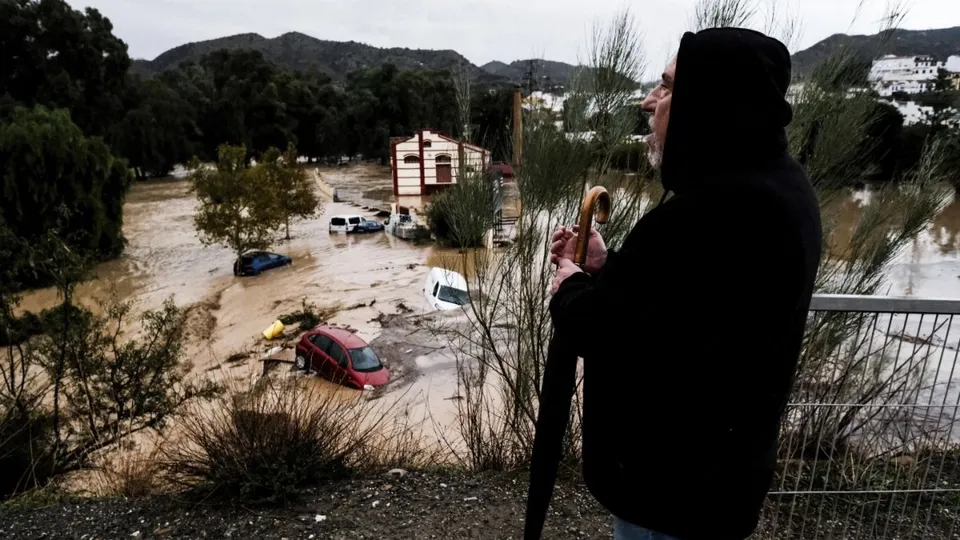 A man observes several cars being swept away by the water, after floods preceded by heavy rains caused the river to overflow its banks in the town of Alora, Malaga, Spain, Tuesday, Oct. 29, 2024