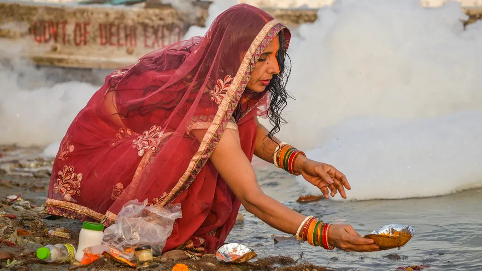 A devotee performs rituals on the bank of the Yamuna river as toxic foam floats on the surface of the polluted river during the start of the 4-day Chhath Puja festival, at Kalindi Kunj in New Delhi, Tuesday, Nov 5, 2024