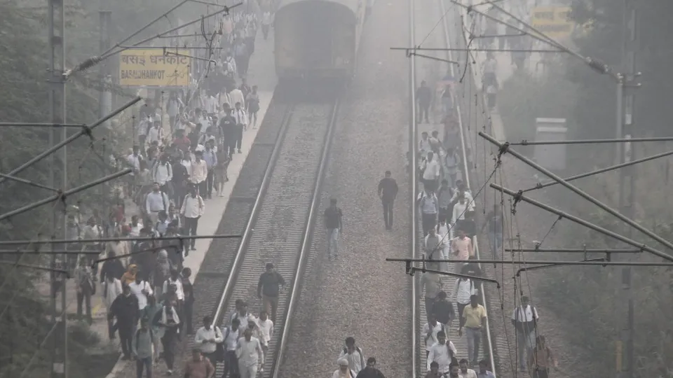 People walk on the railway tracks amid low visiblity due to smog in Gurugram