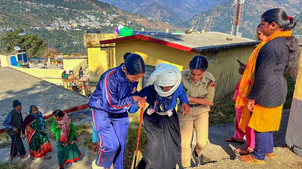 An elderly voter being assisted to a polling booth to cast her vote during the Kedarnath Assembly constituency bypoll, in Rudraprayag, Uttarakhand.