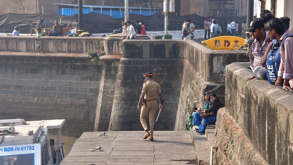 A police personnel keeps vigil at the coast as people look on following an incident where a ferry capsized off the Mumbai coast when a Navy craft crashed into it on Wednesday, in Mumbai, Thursday, Dec. 19, 2024.