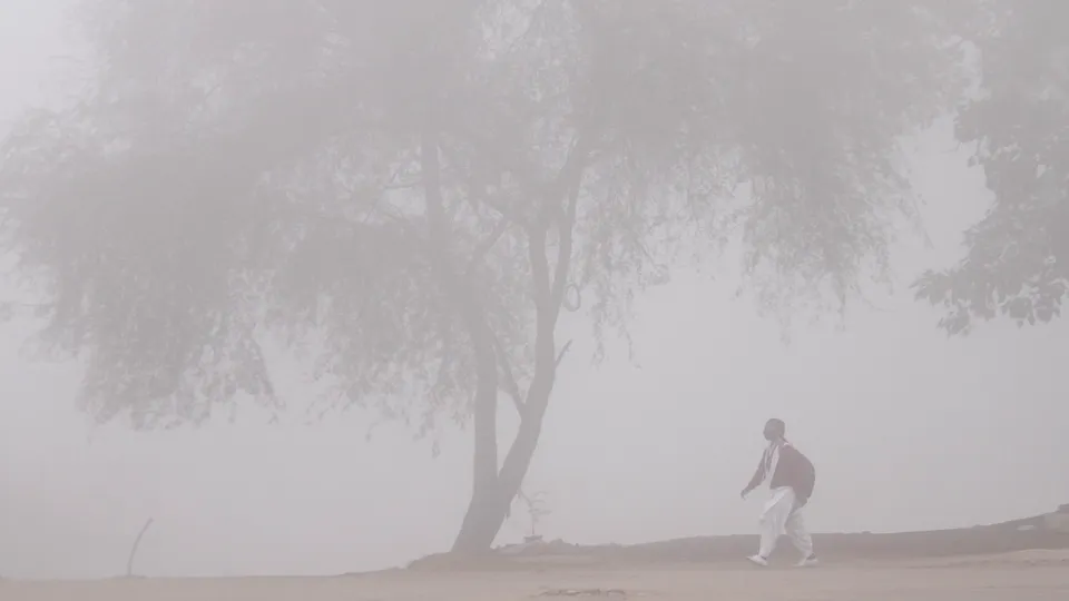 A student walks to her school amid low visibility due to fog, during a cold winter, in Gurugram, Thursday, Dec. 19, 2024.