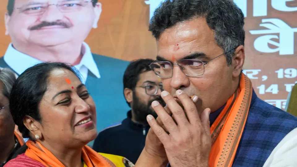 Rekha Gupta offers sweets to party leader Parvesh Verma after BJP legislature party meeting, at the party office in New Delhi on Wednesday, Feb. 19, 2025.