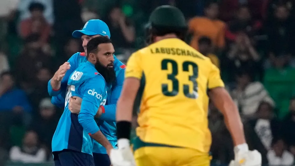 England's Adil Rashid, left, celebrates with Jos Buttler after the dismissal of Australia's Marnus Labuschagne, right, during the ICC Champions Trophy cricket match between Australia and England in Lahore, Pakistan on Saturday, Feb. 22, 2025.