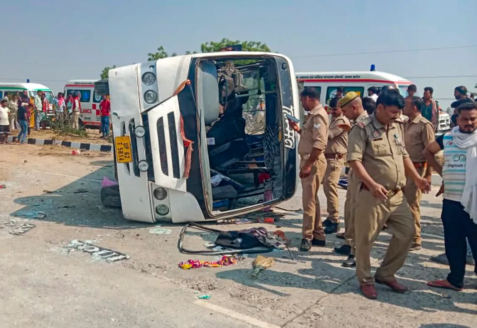 Police personnel and others stand near an overturned vehicle after an accident, in Jaunpur, Uttar Pradesh.
