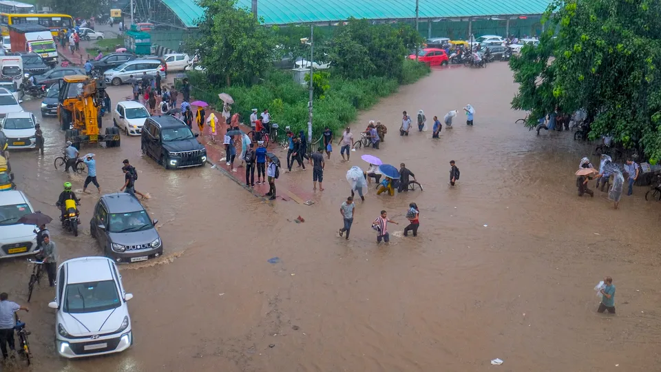Commuters make their way through a waterlogged road amid rainfall, in Gurugram, Monday, Sept. 1, 2025.