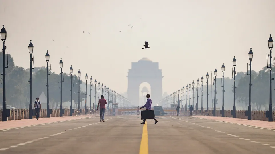 People walk along a road amid low visibility caused by worsening air quality, with India Gate shrouded in haze in the backdrop, in New Delhi, Friday, Oct. 17, 2025.