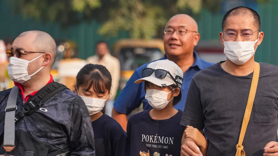 Foreign tourists wearing face masks visit Kartavya Path during a smoggy winter morning, in New Delhi, Saturday, Nov. 22, 2025.
