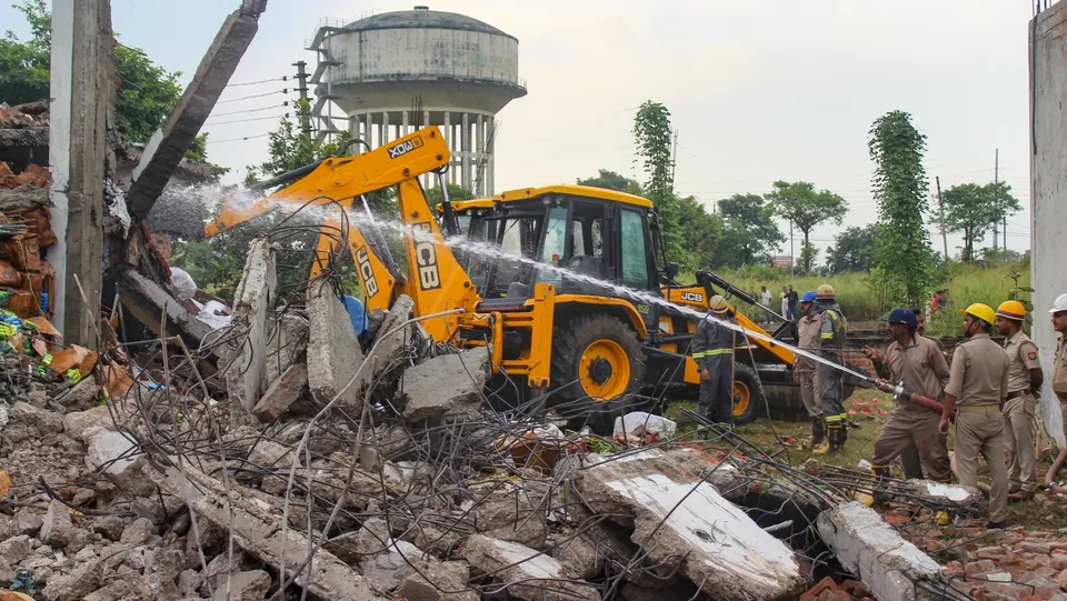 Police personnel and firefighters at the site after an explosion at a soap-making factory, at Lohia Nagar in Meerut